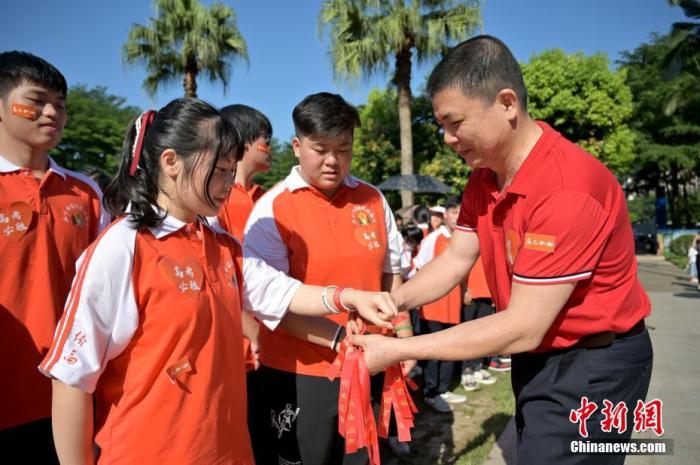 資料圖：廣西華僑實(shí)驗(yàn)高中的教師為高三學(xué)子系上紅絲帶，盼望學(xué)子高考必勝。 俞靖 攝