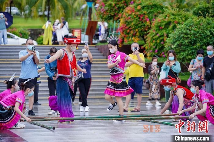 資料圖：三亞大小洞天旅游區(qū)入口，工作人員跳竹竿舞迎接游客。 駱云飛 攝